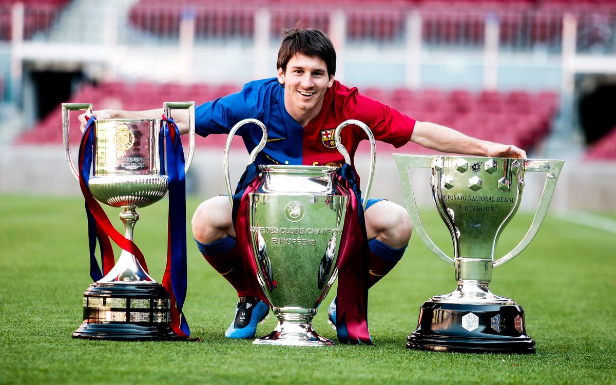 Leo Messi pose avec les trophées du triplé 2009: Coupe du Roi, Ligue des Champions et Liga